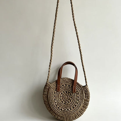 Round woven handbag with brown handles on a light gray background