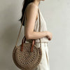 Person holding a woven handbag with a plain background