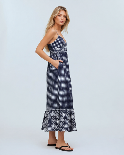 Summer gingham maxi dress featuring slim straps, a V-neck bodice, side pockets, and a ruffled lower hem.