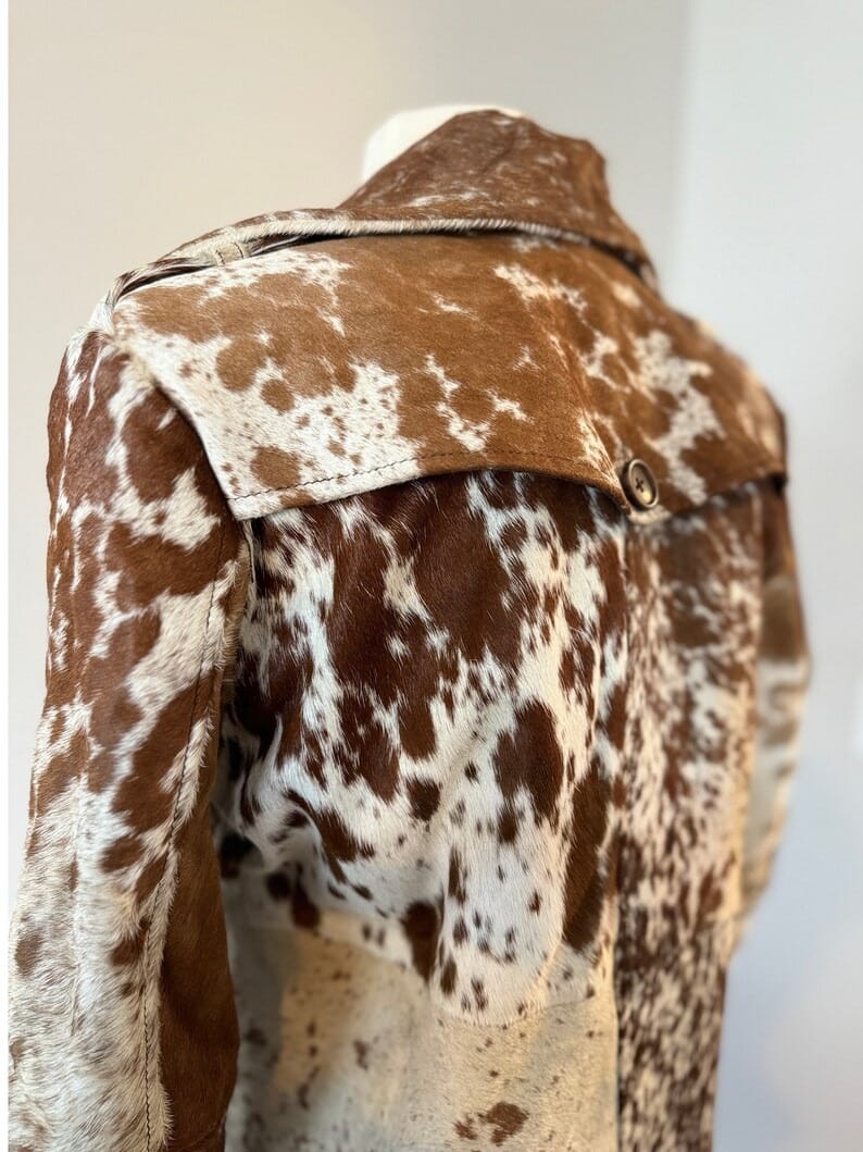 Women’s black brown white cowhide coat with button-down trench cut. Unique fur texture ideal for rodeo events and southern gatherings.