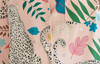 A close-up of a pink button-front shirt or jacket featuring a tropical and safari print with a large spotted leopard, palm leaves, blue flowers, and green foliage.