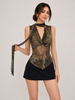 A woman modeling a sleeveless halter-neck top with a dark olive green and brown camouflage pattern, paired with a black mini skirt, against a light gray studio background.