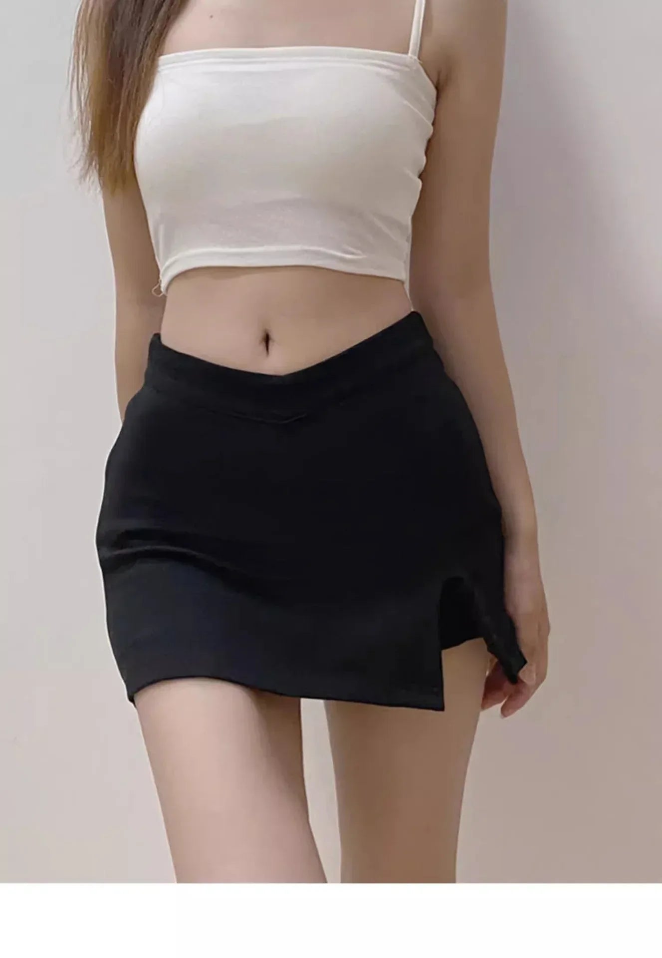 Women’s fitted black skirt featuring mini length, medium-stretch fabric, solid finish, and minimal side slit design.