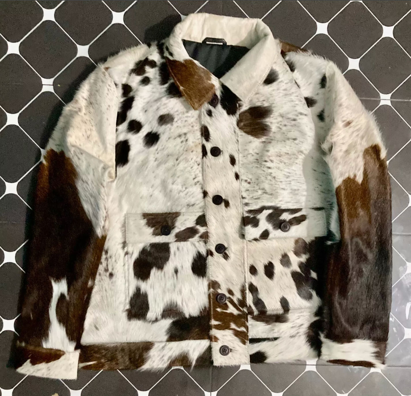 Women's cow jacket made from genuine cowhide with button front, flap pockets, and full hair-on detail. Bold cow coats design perfect for ranch or streetwear.

