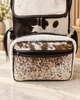 Cowhide mommy backpack with brown leather flap opened above natural hair-on hide and visible zippered storage compartments.