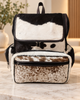 Cowhide mommy backpack in brown and white hair-on hide with flap top, leather trim, and front zip pocket.