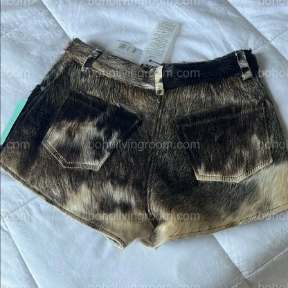 Real cow fur mini shorts featuring black, brown, and white tricolor hide. Designed for women seeking authentic cowhide fashion with a rugged edge.