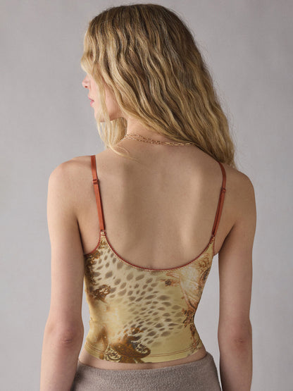 A woman shown from the back wearing a beige and brown leopard-print camisole top with thin brown straps, set against a plain gray studio background.