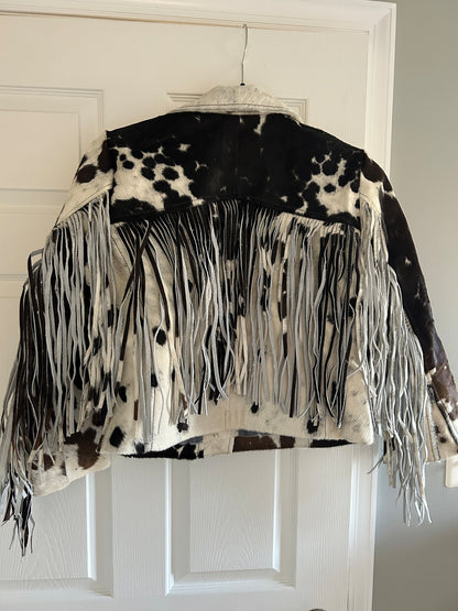 Real cowhide jacket for women and men with striking black and white cow print, cropped fit, and flowing fringe for standout Western-style fashion.

