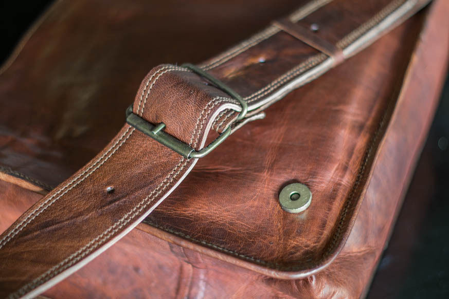 Premium leather men’s messenger bag with a structured design and polished hardware, displayed on a sleek marble countertop.