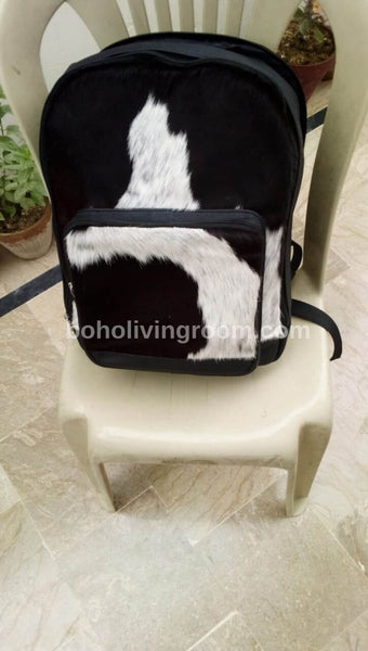 Rustic cowhide backpack on wooden bench.