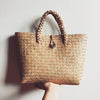 Handwoven seagrass rattan bag with natural braided handles. A unique summer bag perfect for beach days, markets, and casual outings.