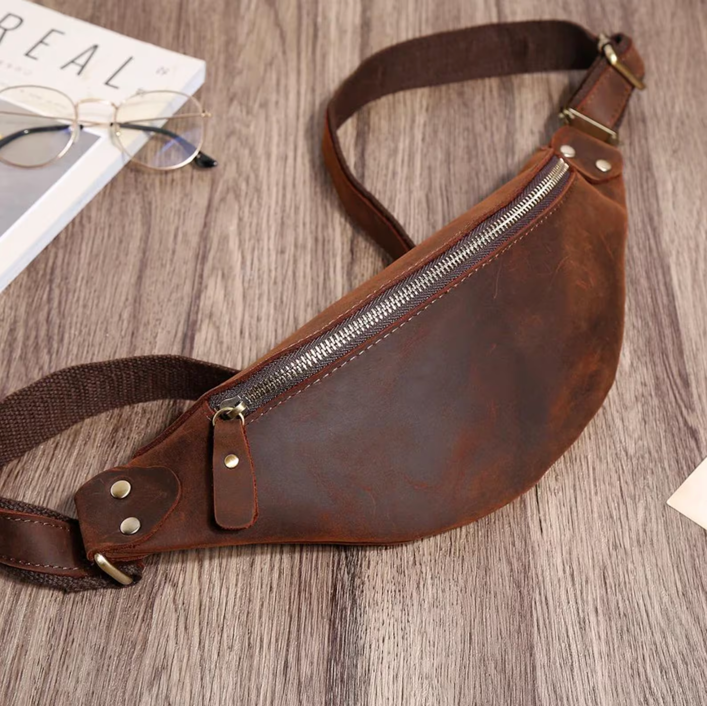 Stylish tan leather messenger bag hanging from a chair, showcasing its elegant design and texture.