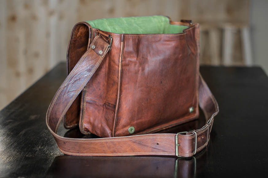 Sleek leather men’s messenger bag with a minimalist design, styled next to a laptop and coffee cup on a desk.