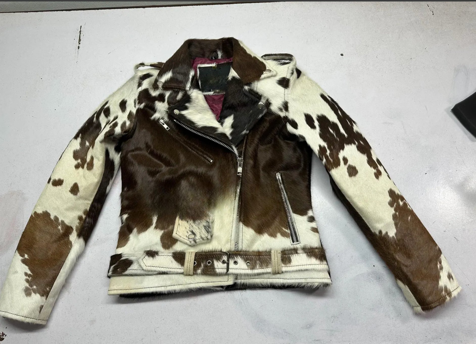 Authentic tricolor cowhide jacket for men with real fur, natural hide pattern, biker zipper design, and waist belt. Bold Western cowhide coat for statement wear.

