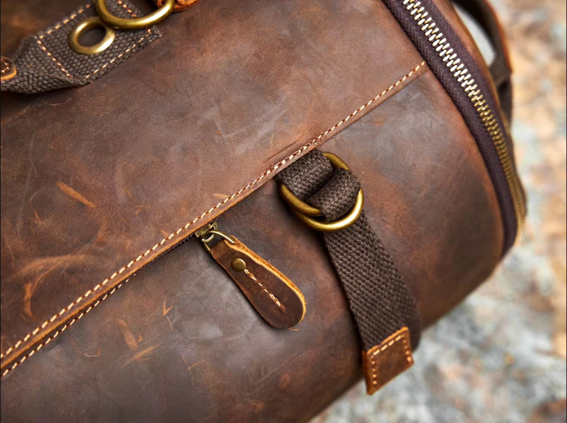 Vintage-style leather duffle backpack with durable straps, multiple compartments, and a polished finish, displayed outdoors.