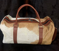 This cowhide duffle purse is the perfect companion for your next adventure. Lightweight and durable, it offers a spacious main compartment and an inside pocket for organizing all of your belongings.