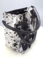 A cowhide shoulder bag is a type of handbag that is typically worn with the strap over the shoulder and looks stunning with a fringe, made in black and white. 