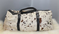 One of its kind cowhide duffle cowhide leather bag with silver zipper closure custom made to over long leather strap very easy to adjust and pocket to keep your keys, iphone or shades. 