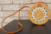 Handcrafted rattan bag in a boho design, paired with flowers and sunglasses, perfect for a summer vibe.