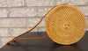 Modern rattan bag on a sandy beach with seashell accents, evoking a tropical and relaxed feel.
